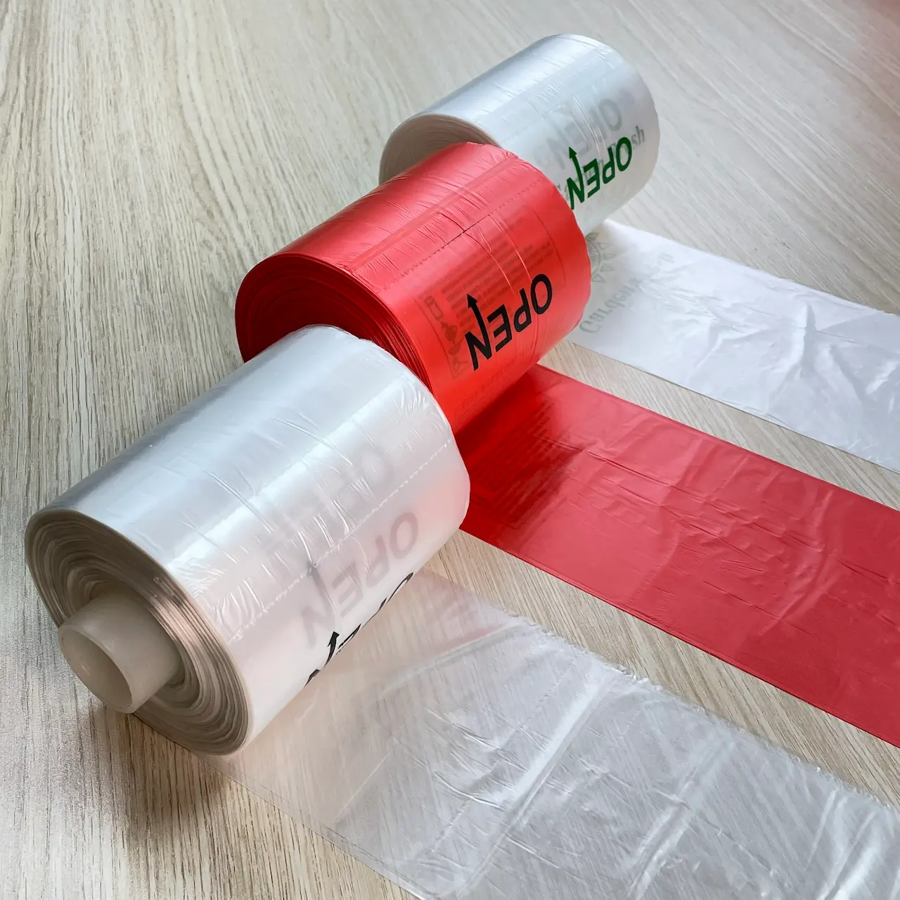 Polyethylene (PE) Plastic Bags in Various Colors and Sizes - Plastic bag manufacturers in vietnam PE plastic bags in red and transparent rolls placed on a wooden table